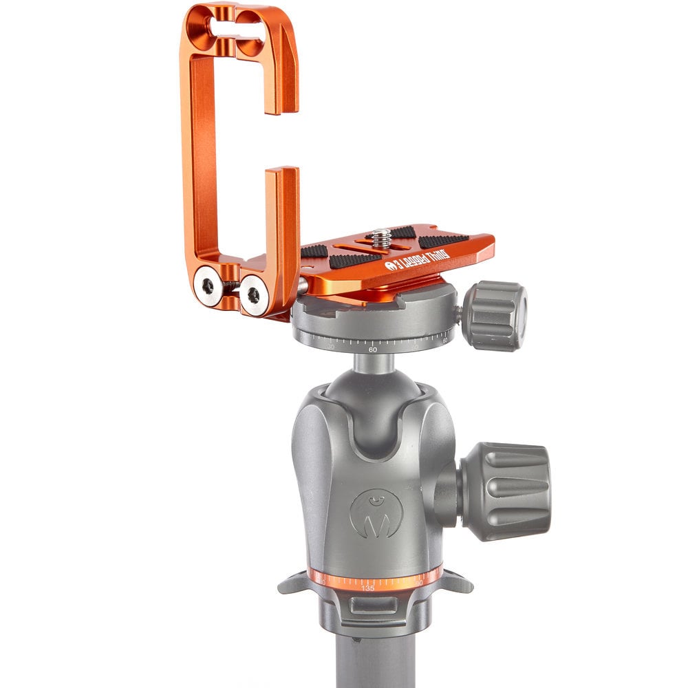 Camera tripod head with orange quick release plate on a white background