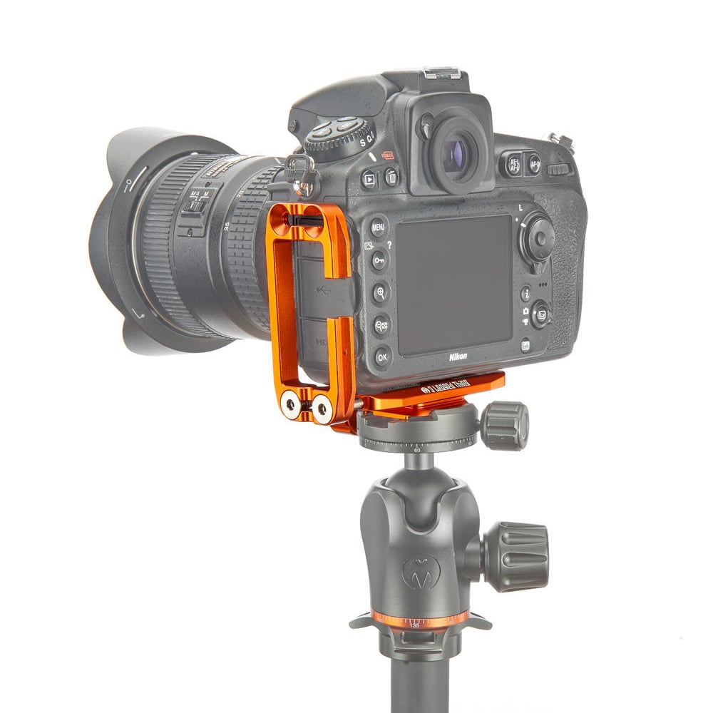 Camera mounted on a tripod with an orange and gray attachment on a white background
