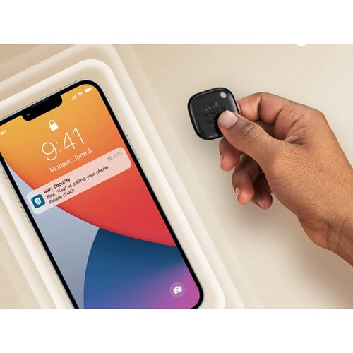 Hand holding a small device next to a smartphone with a colorful display.