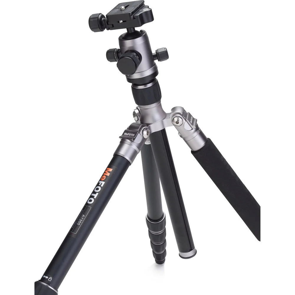 MeFoto RoadTrip aluminium tripod with reverse-folding legs, extending to 156.5 cm, supporting up to 8 kg, and converting into a full-size monopod via a removable foam-cushioned leg. Features two-position leg angle stops, spring-loaded centre column hook, Arca-type quick release plate, double action ball head with 360° pan, and included carry case.