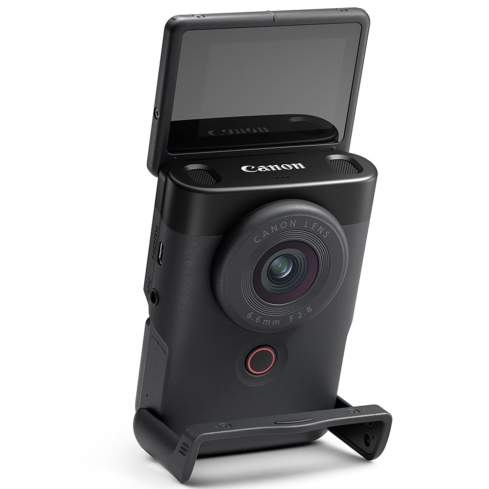 Canon PowerShot V10 Vlog Camera in black, compact rectangular body with wide-angle lens, tilting flip-up screen, and built-in stand.