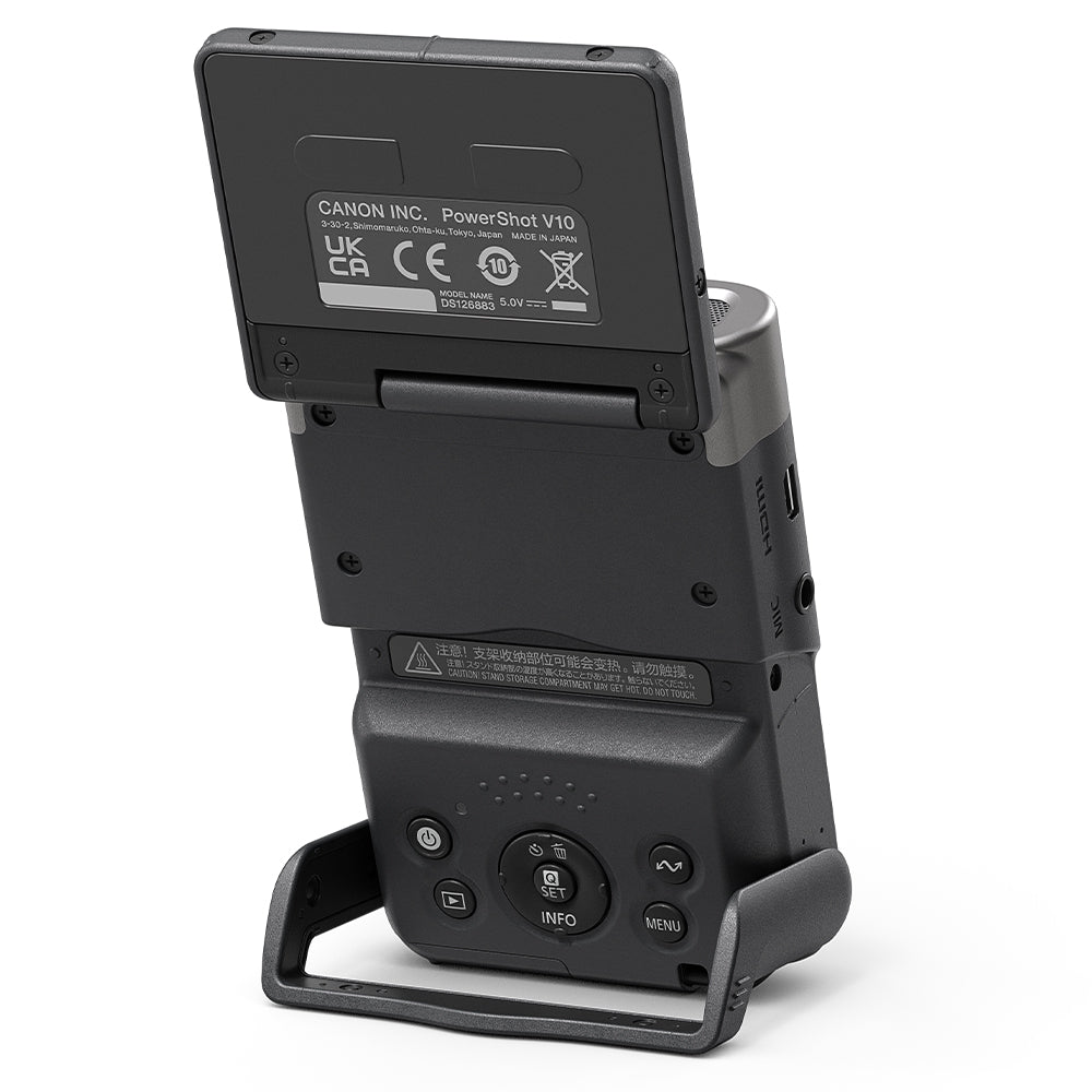 Canon PowerShot V10 Vlog Camera in black, compact rectangular body with wide-angle lens, tilting flip-up screen, and built-in stand.