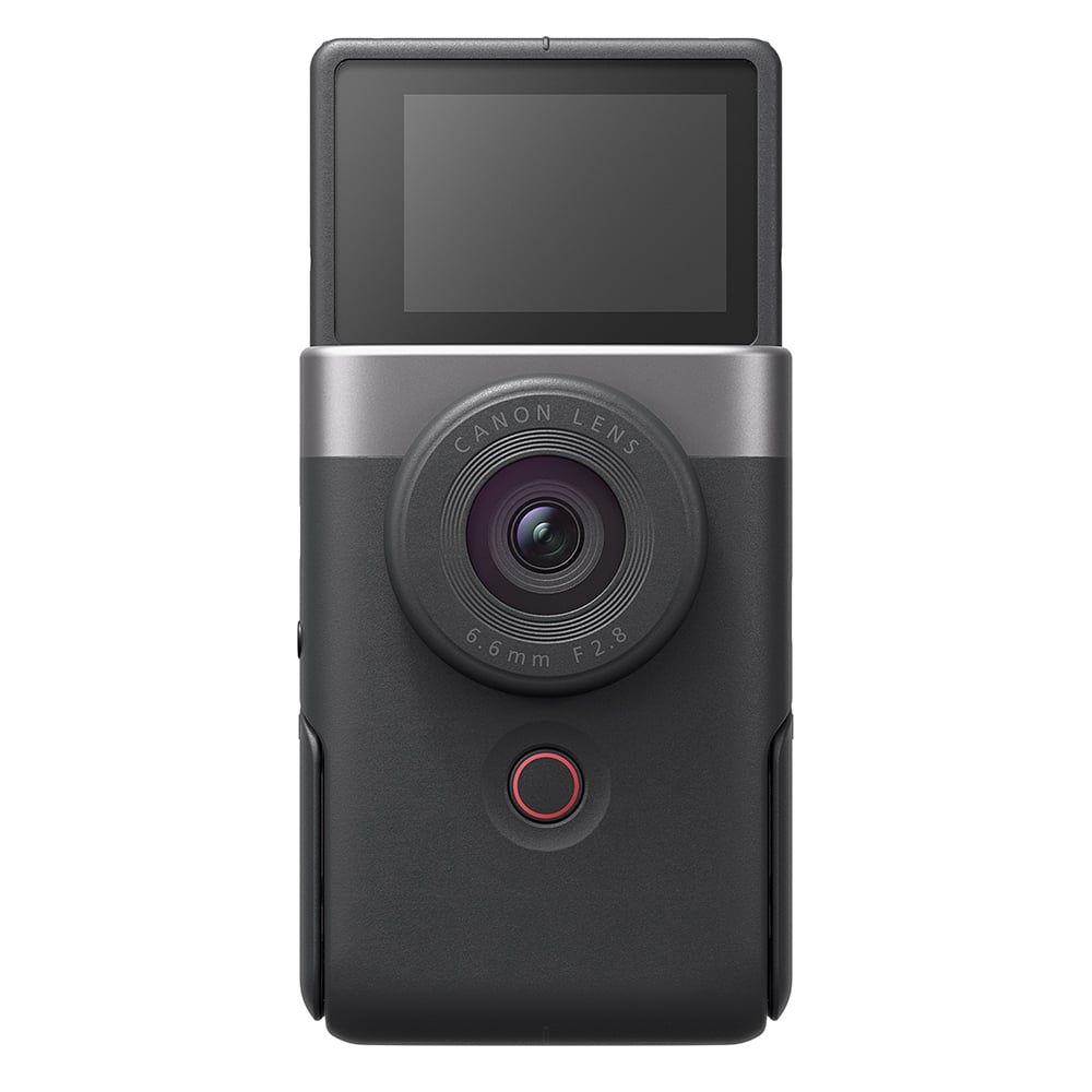 Canon PowerShot V10 vlog camera kit in silver — compact rectangular camera with wide-angle lens, flip-up screen, and integrated mini tripod stand.