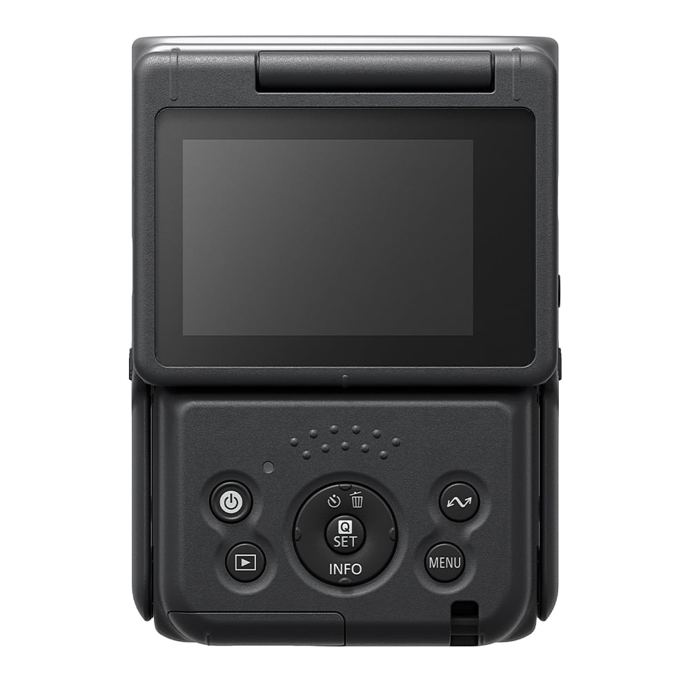 Canon PowerShot V10 vlog camera kit in silver — compact rectangular camera with wide-angle lens, flip-up screen, and integrated mini tripod stand.