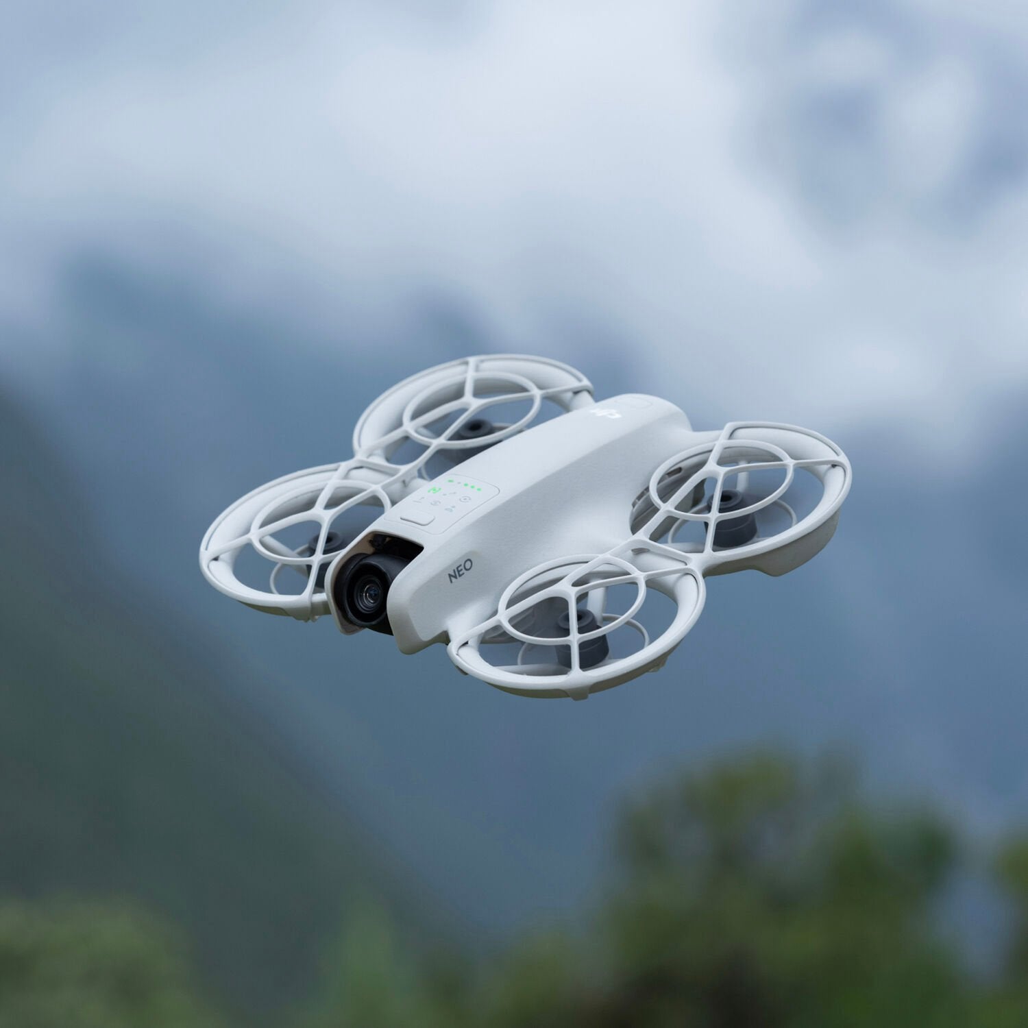 White drone flying against a blurred natural background