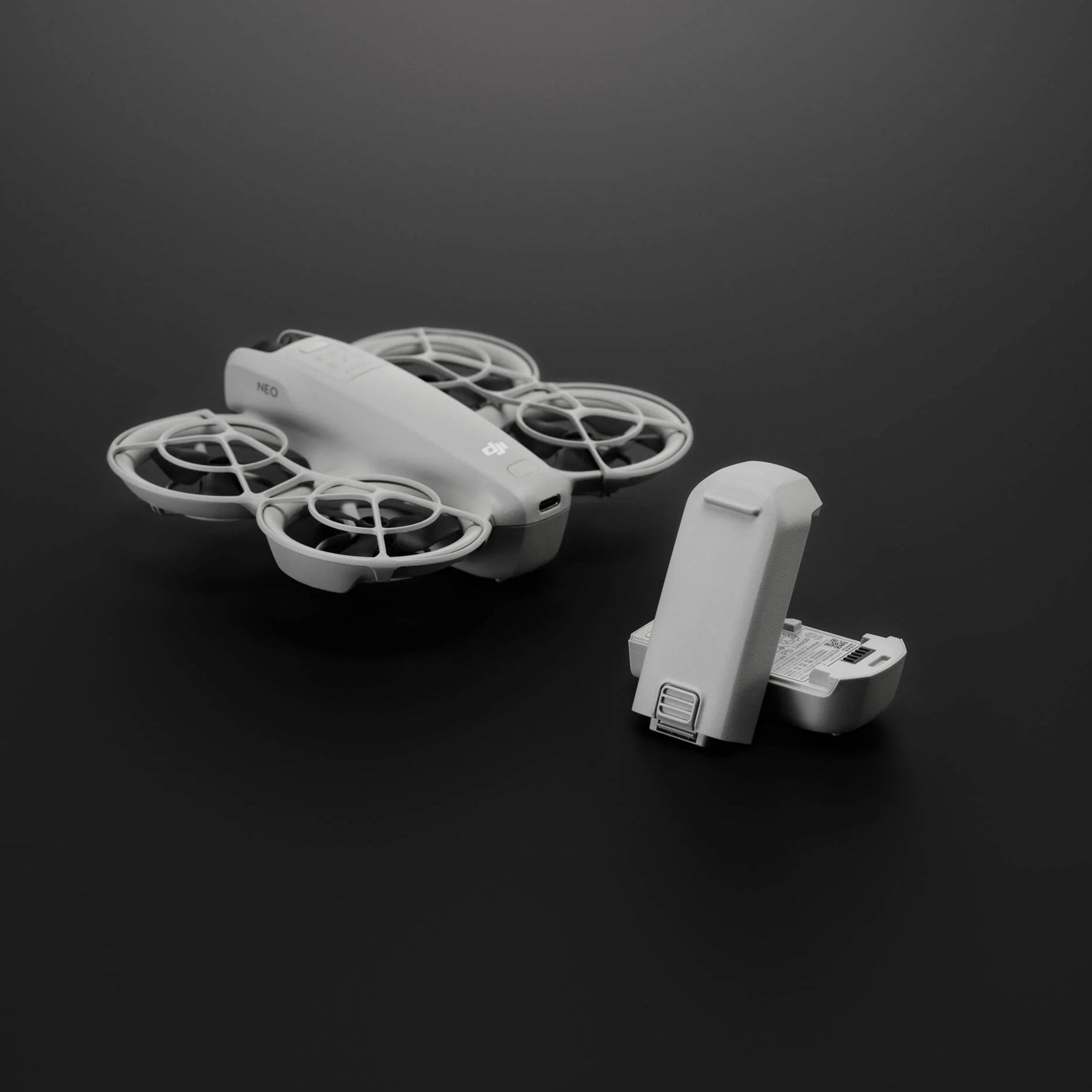 White drone with propellers and a extra batteries on a black background