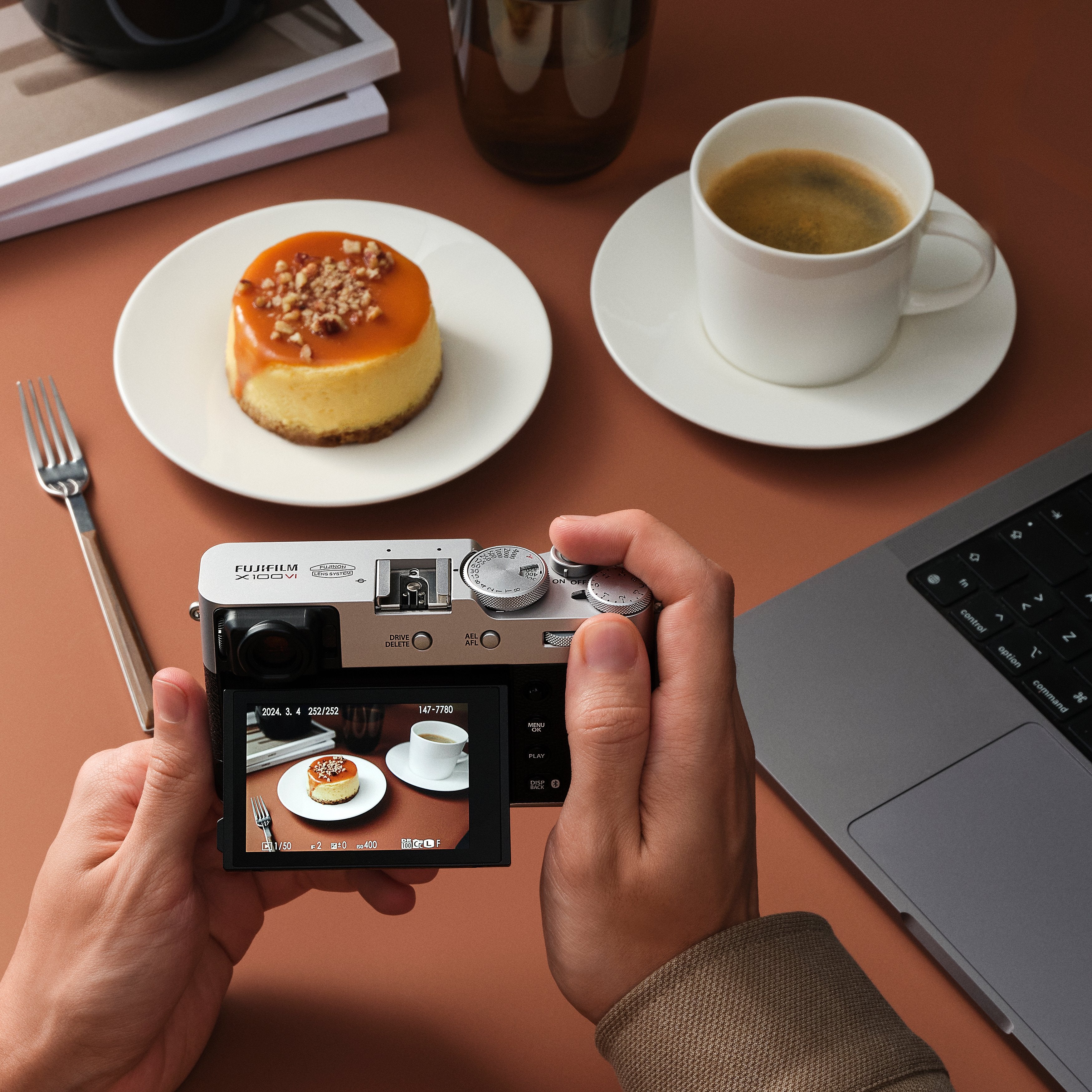 Fujifilm X100VI silver compact camera with 40.2MP APS-C X-Trans CMOS 5 HR sensor, 23mm f/2 fixed lens, 5-axis in-body image stabilization, hybrid optical/electronic viewfinder, 6.2K video recording, and 3-inch tilting touchscreen.