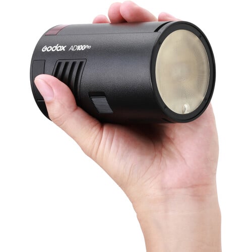 Hand holding a cylindrical Godox AD100Pro light on a white background
