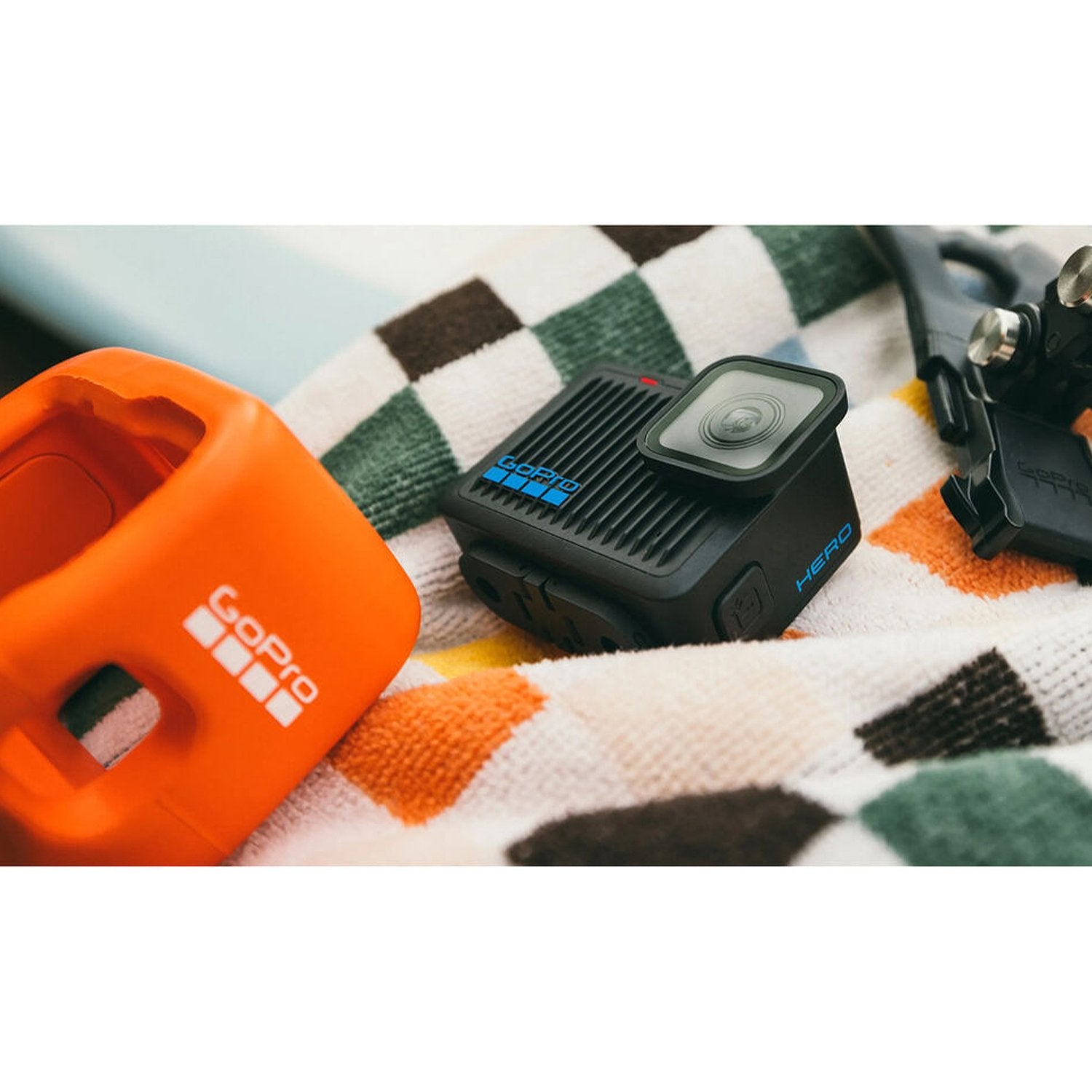 Black action camera with orange protective case on a checkered fabric background