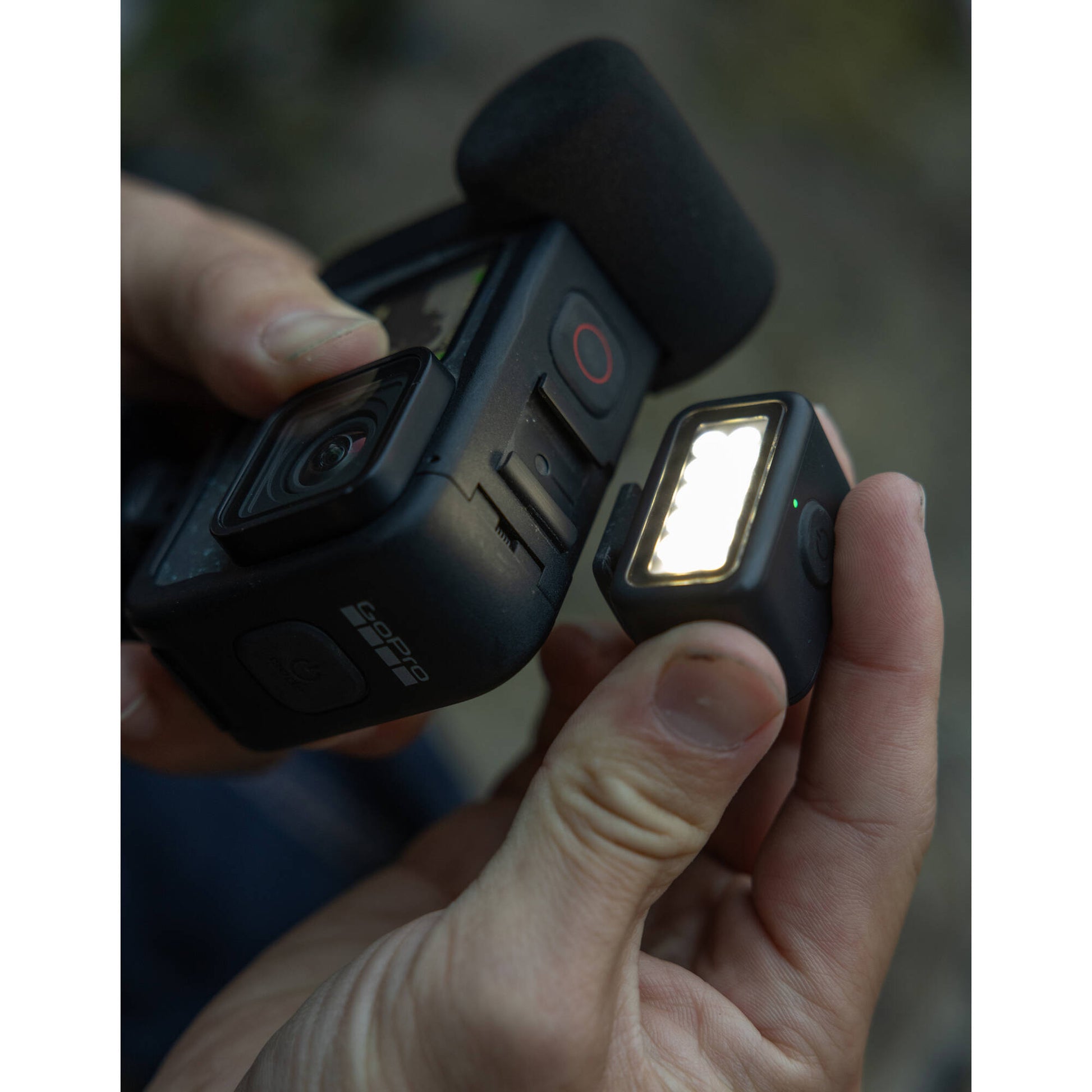 Hand holding a camera with a light attached, blurred background