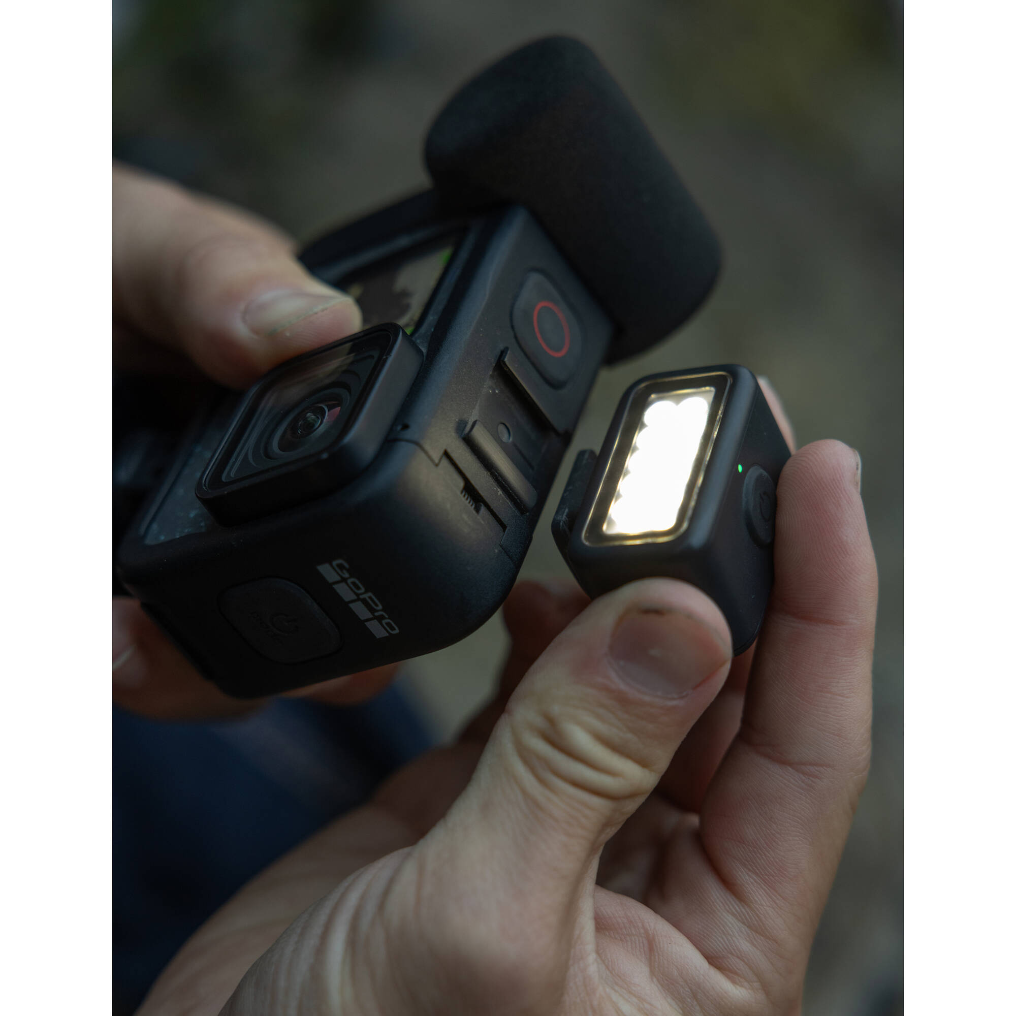 Hand holding a camera with a light attached, blurred background