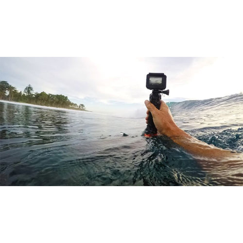 Hand holding a camera above water with a scenic background