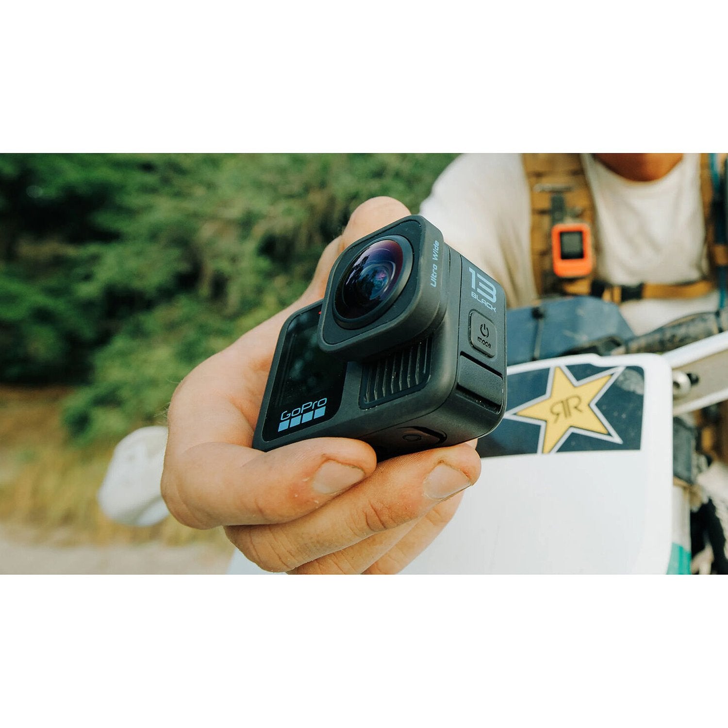 Hand holding a GoPro camera with a blurred outdoor background