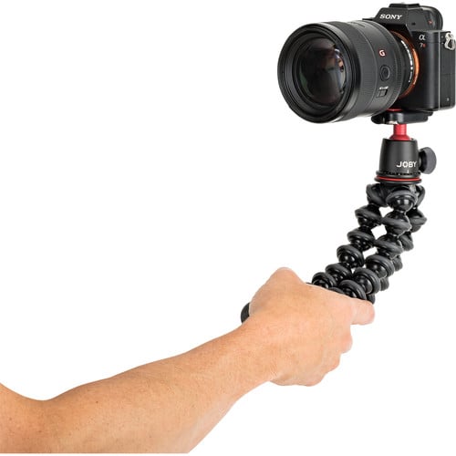 Camera mounted on a Joby gorilla pod held by a person's hand against a white background