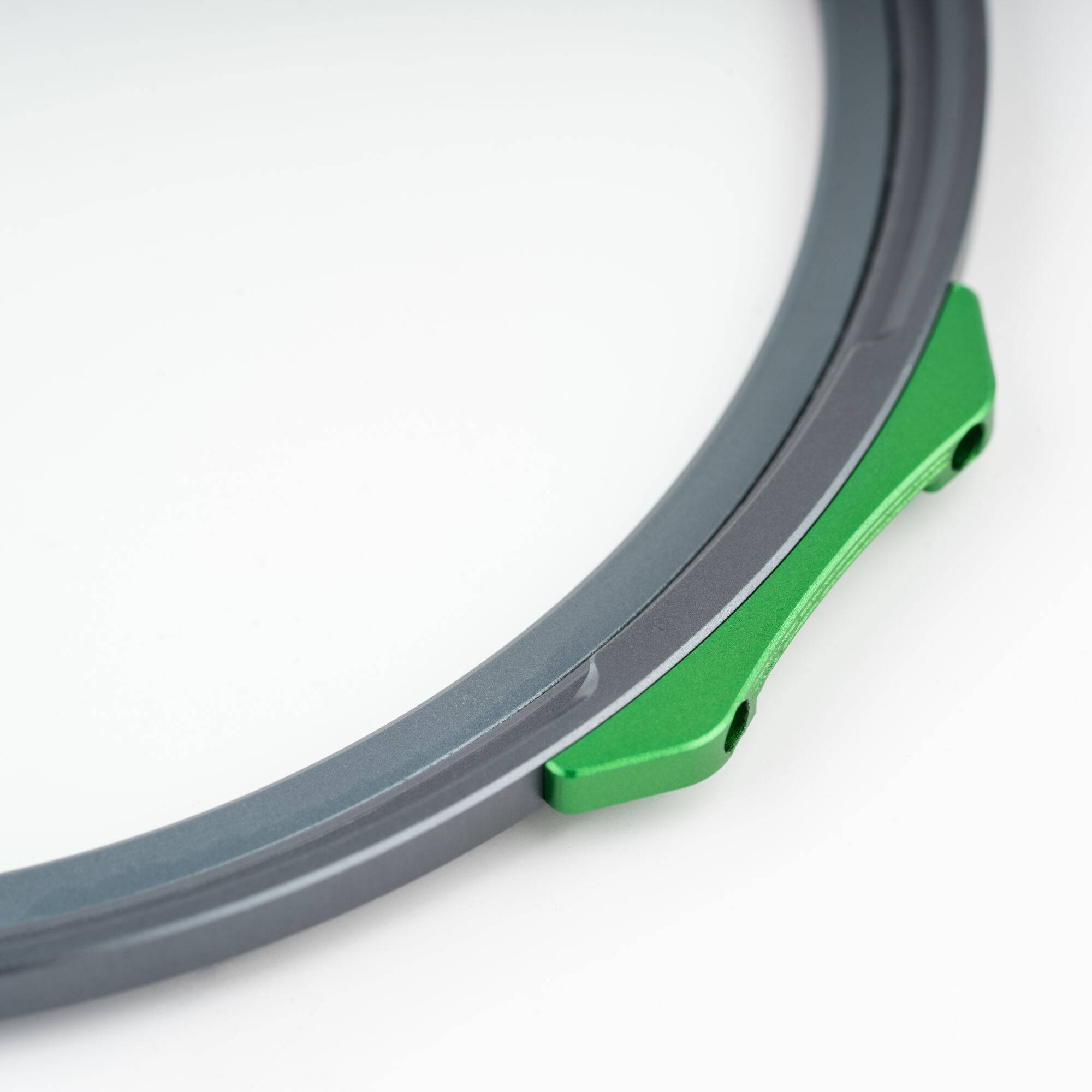 Close-up of a mechanical component with a green metal piece and gray rubber ring on a white background