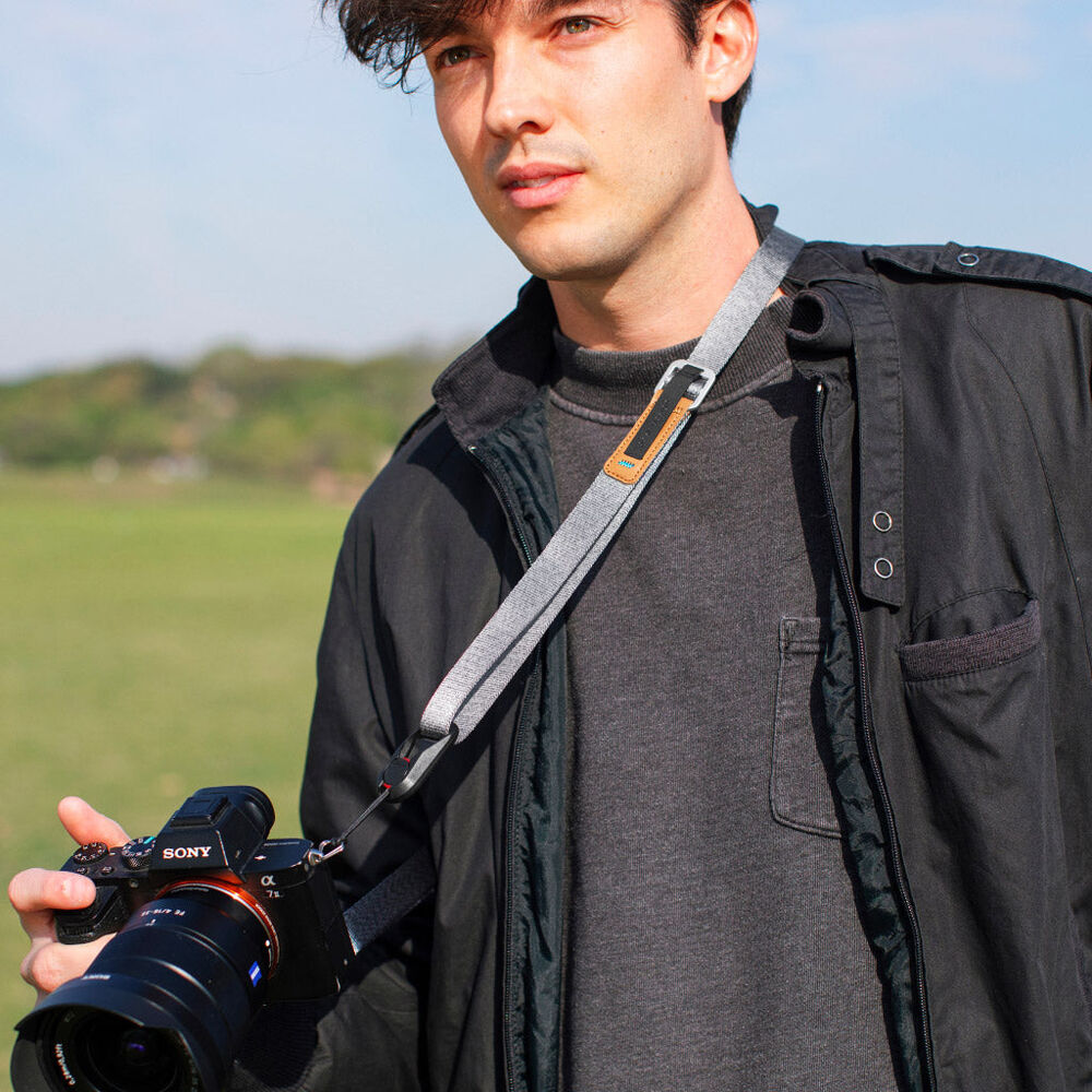 Peak Design Leash camera strap in Ash color, adjustable length from 83 to 145 cm, slim nylon webbing with leather accents, quick-adjust aluminum sliders, quick-release anchors rated for 90 kg, versatile for neck, shoulder, or cross-body carry.