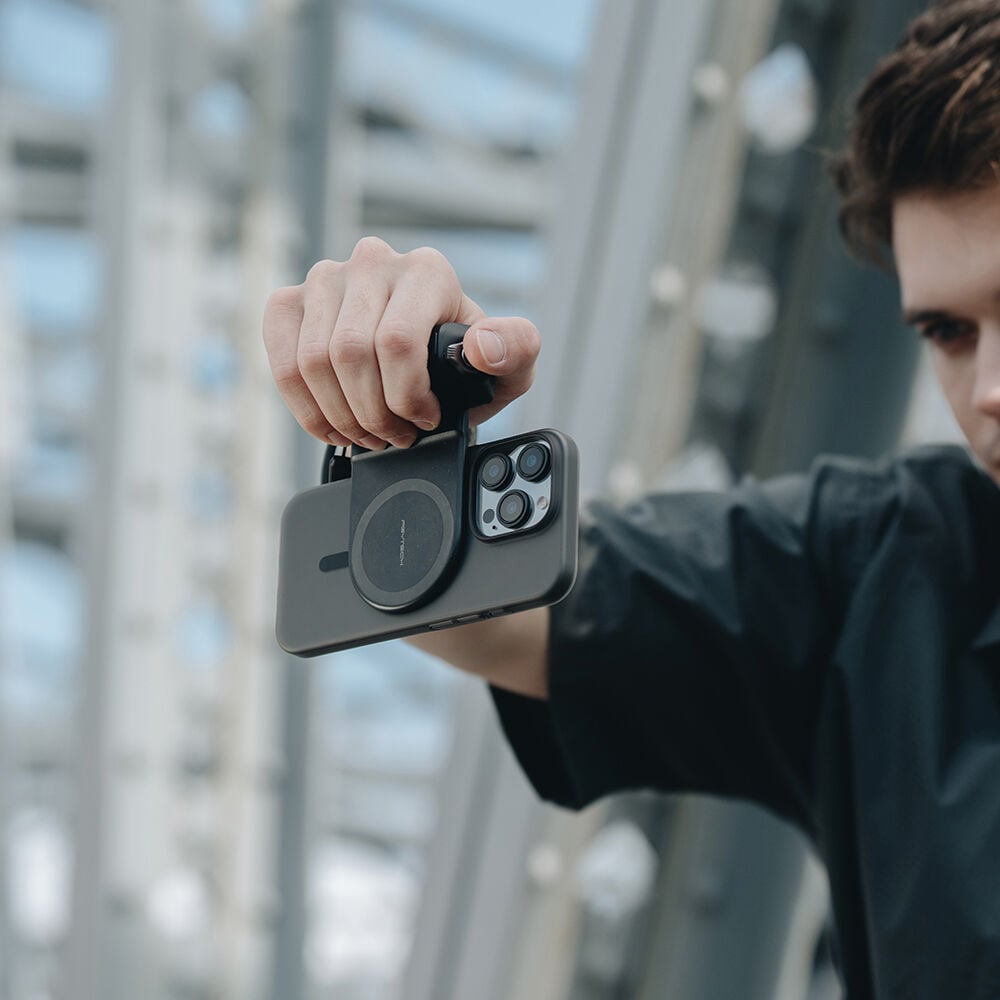 Person holding a smartphone with a camera lens cover in an urban setting