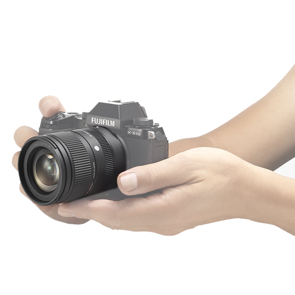Hand holding a Fujifilm camera against a white background