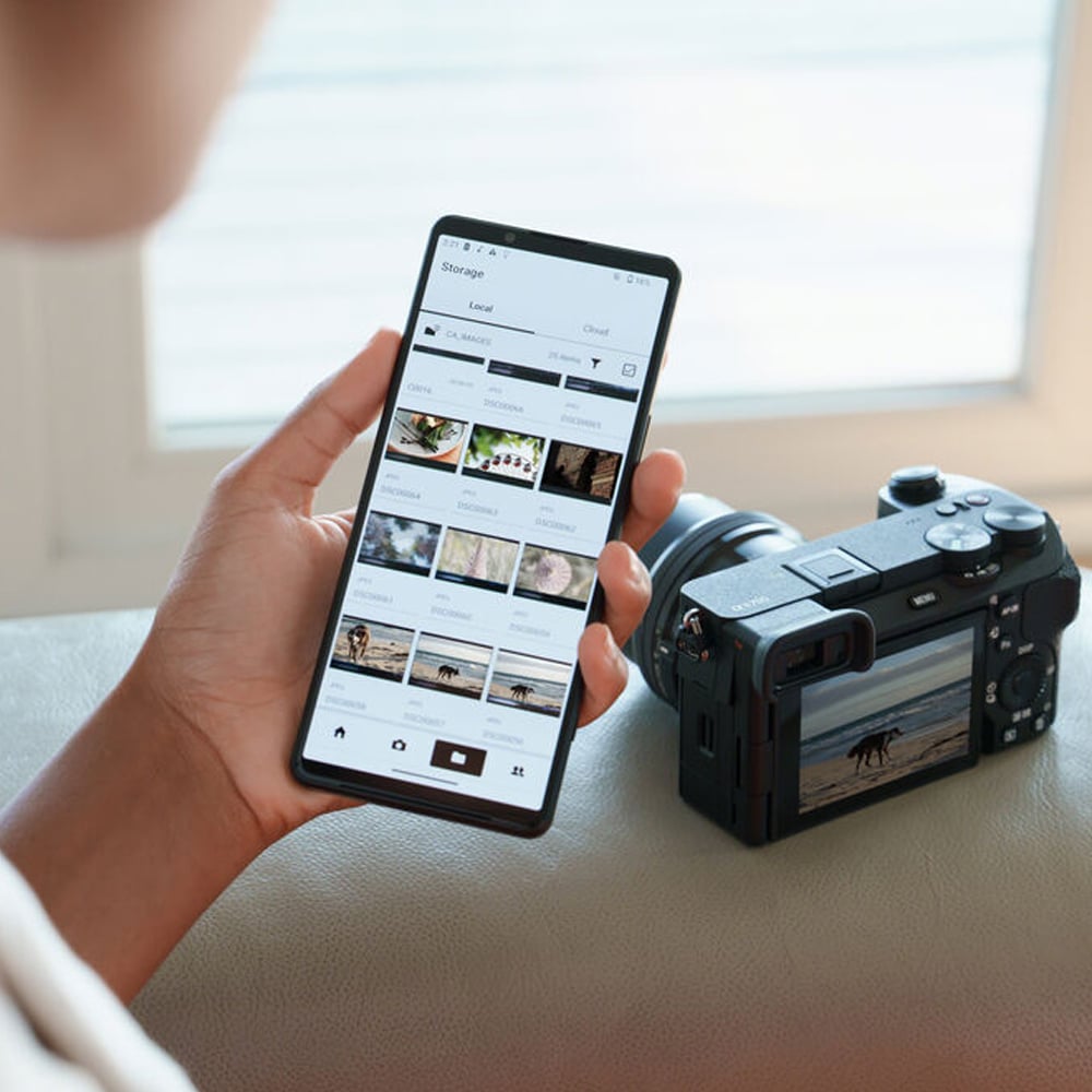 Person using a smartphone app on a table with a camera beside it