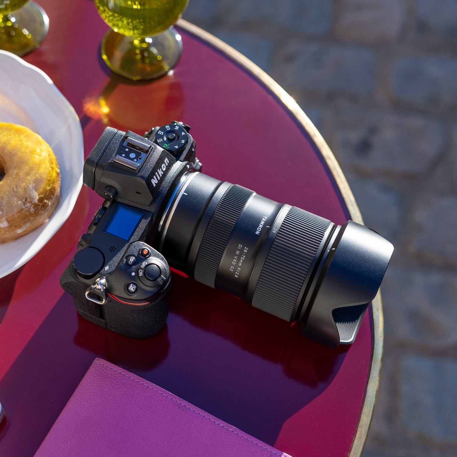 Camera on a table with donuts and glasses in the background