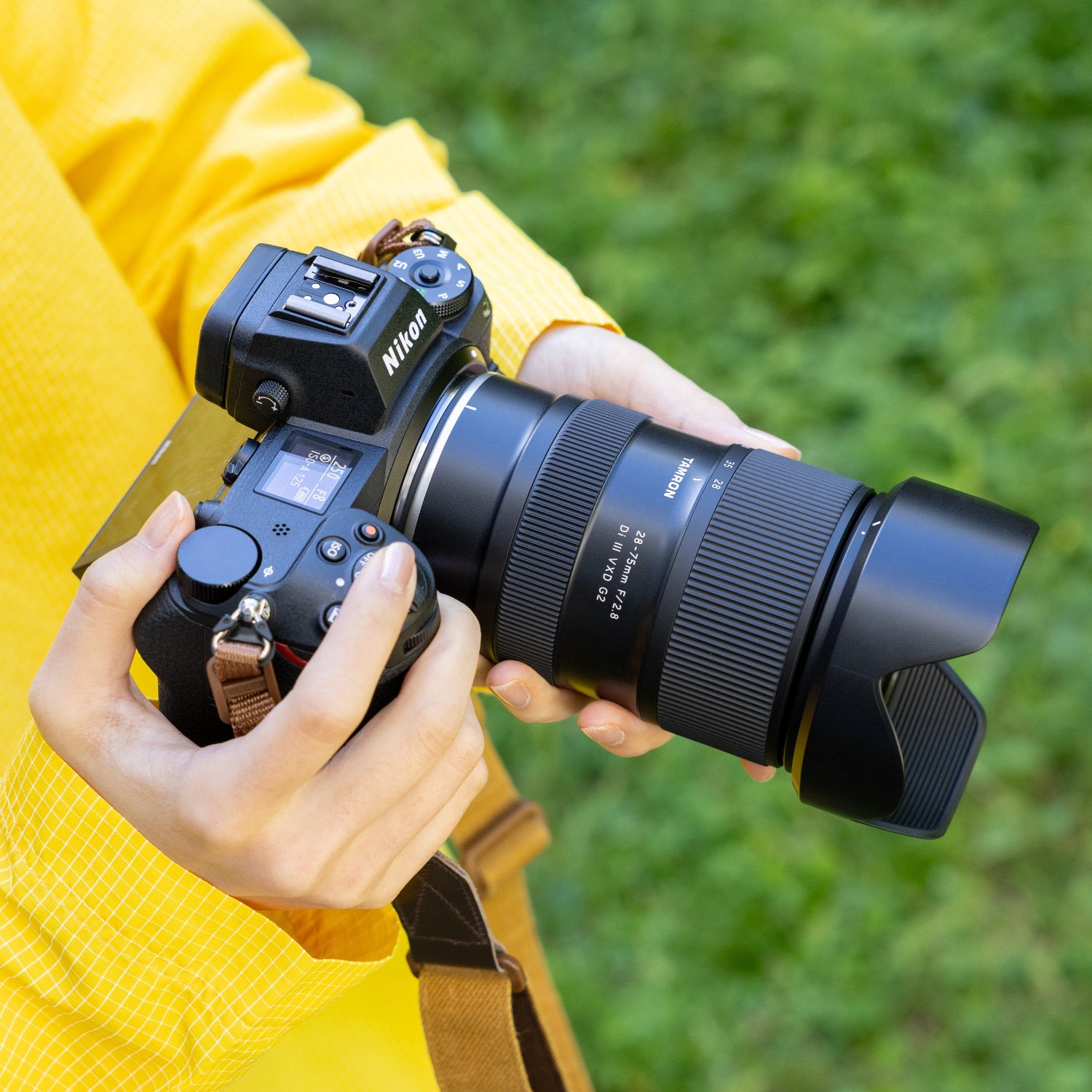 Person holding a camera with a lens on a grassy background