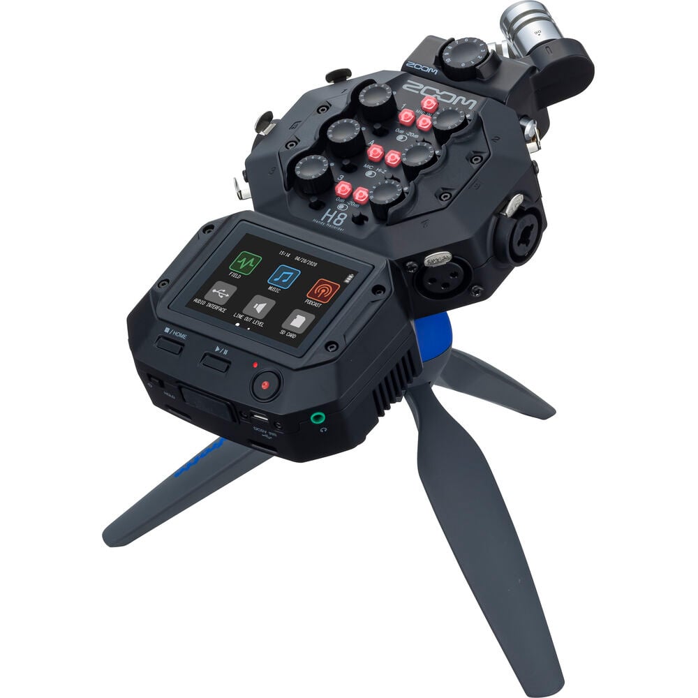 Zoom H8 portable handy recorder showing its color touchscreen, X/Y mic capsule, multiple input gain knobs, outputs and buttons, viewed at slight angle against a neutral background.